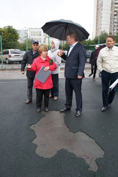 Сергею Митрохину показывают состояние площадки  Москвичи пожаловались и на состояние другой детской площадки, где проходила встреча. Из-за некачественного покрытия в жару площадка очень нагревается, и от нее исходит неприятный запах, некоторым детям становится плохо. Еще в мае площадку обещали переделать, но сейчас говорят, что денег нет.